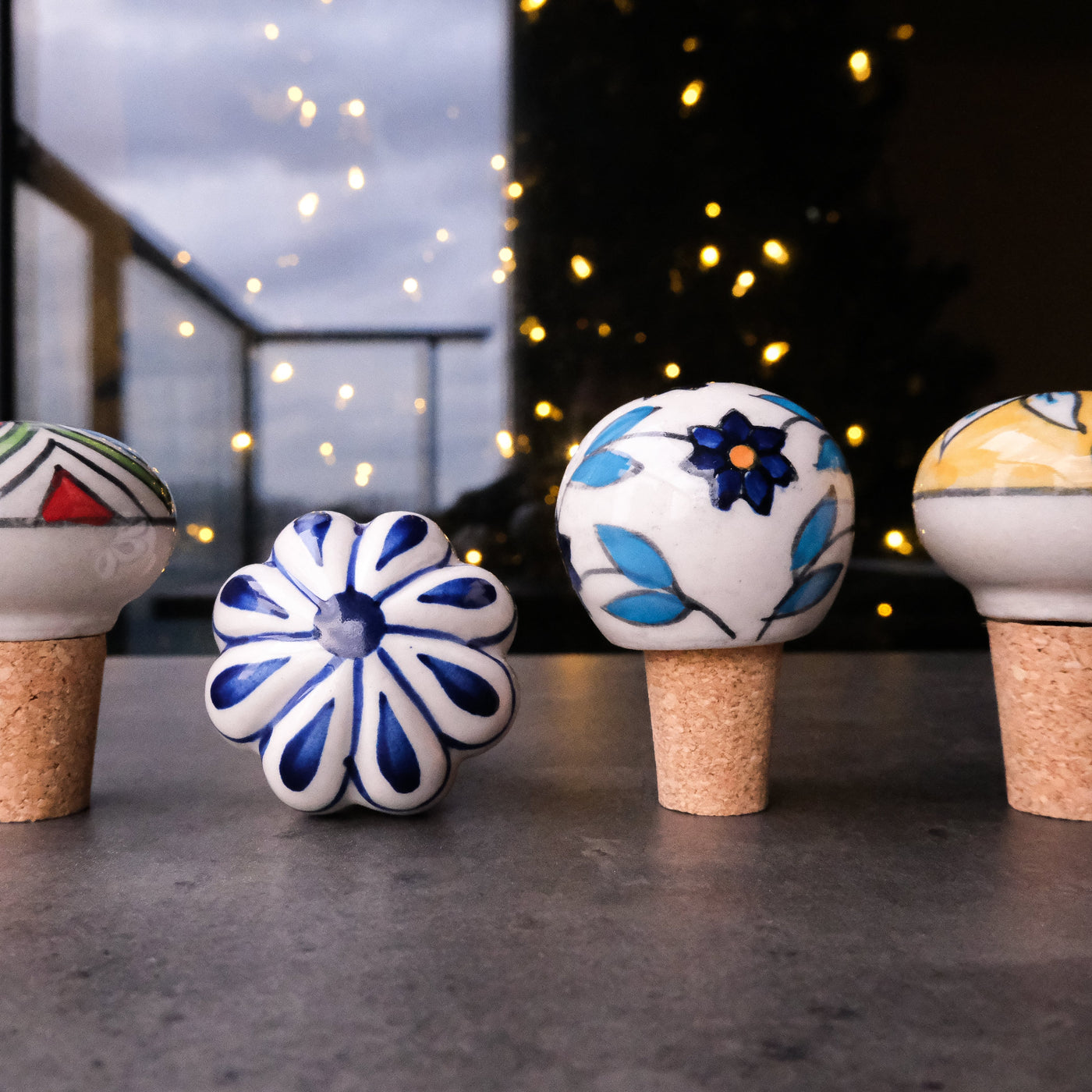Outdoor scene of hand painted ceramic bottle stoppers with cork bases, blue, yellow, green and red colors
