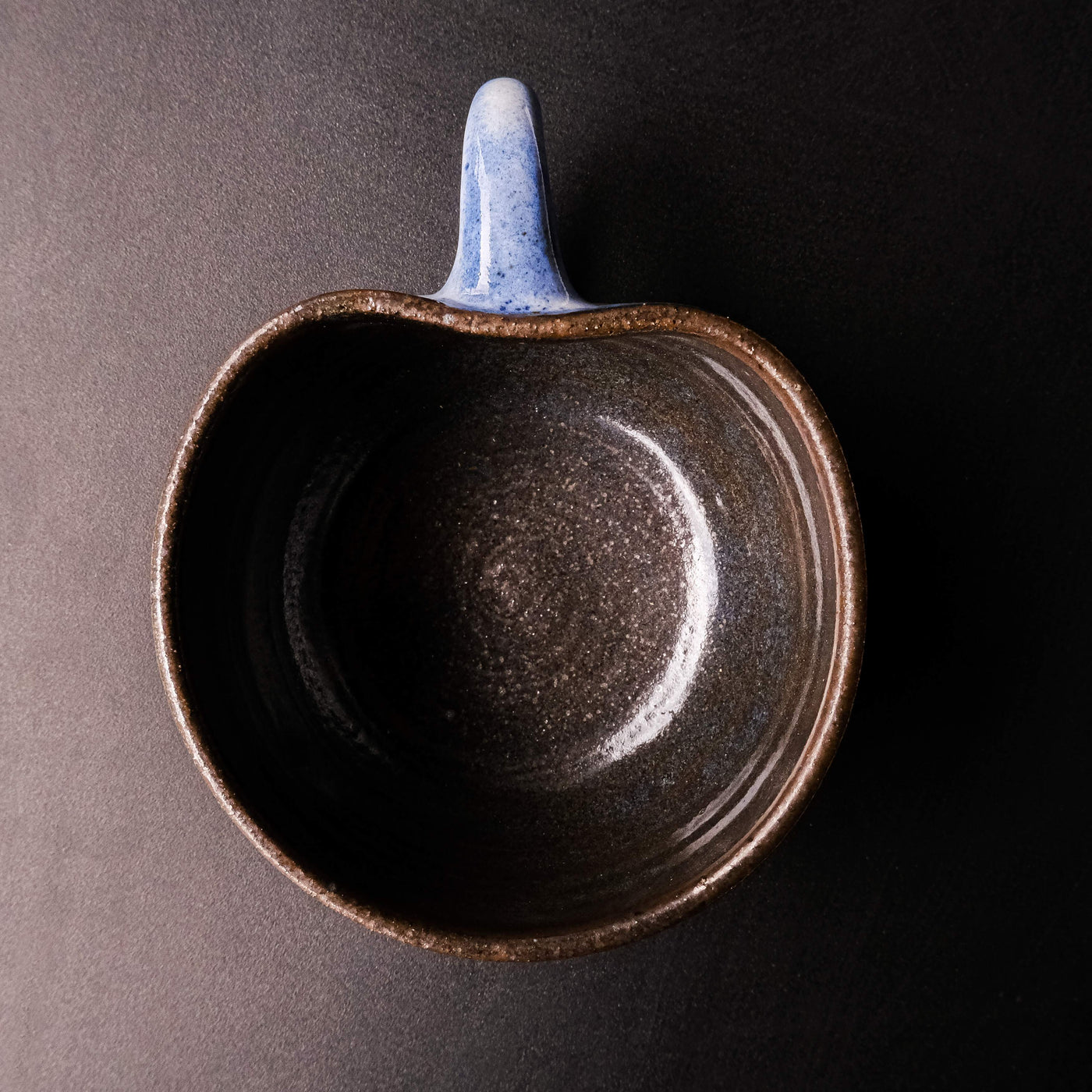 Top angle of a handcrafted blue ceramic mug with speckles, shaped like an apple