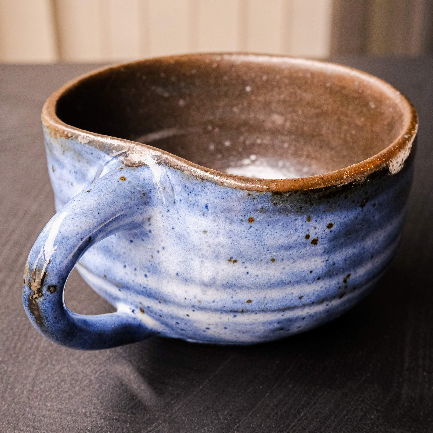 Handcrafted blue ceramic mug with speckles, shaped like an apple