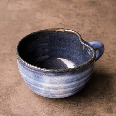 Handcrafted blue ceramic mug with speckles, shaped like an apple